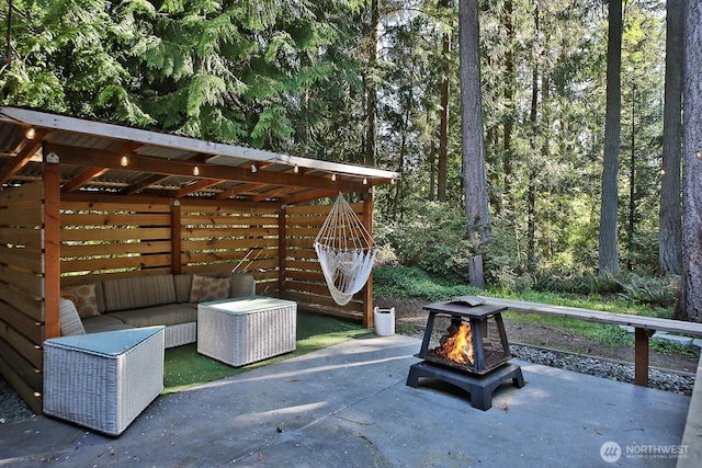 view of patio / terrace with a view of trees and a fire pit