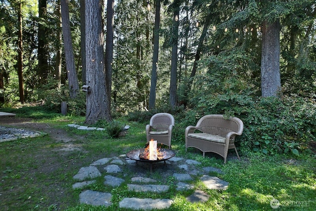 view of yard with an outdoor fire pit and a wooded view