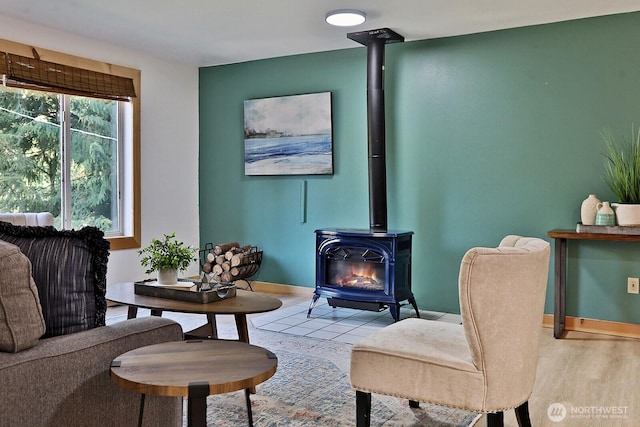 sitting room featuring a wood stove, wood finished floors, and baseboards