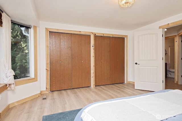 unfurnished bedroom with baseboards, multiple closets, and wood finished floors