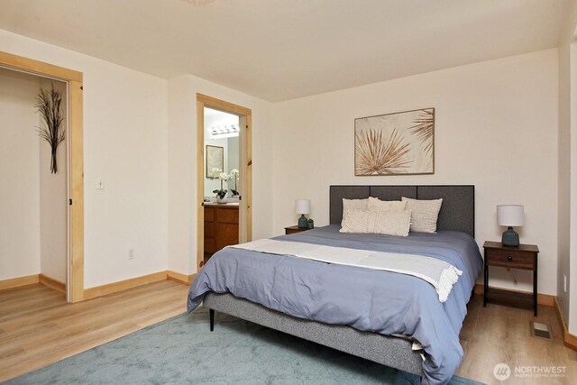 bedroom with ensuite bathroom, baseboards, light wood-type flooring, and visible vents