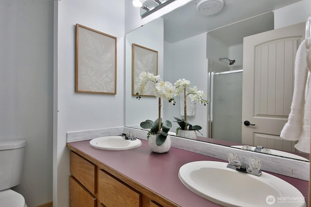 full bath with double vanity, toilet, a shower stall, and a sink