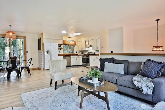 living area with an inviting chandelier, light wood-style flooring, and baseboards