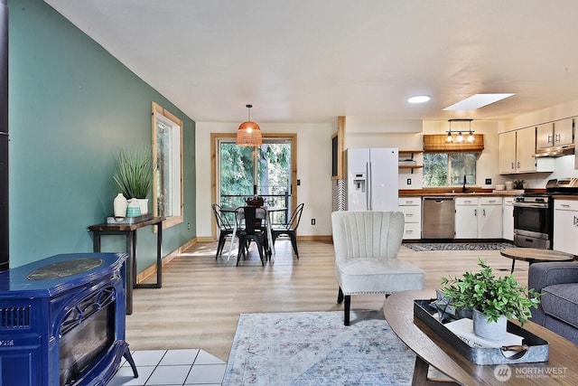 living area featuring a wood stove, plenty of natural light, baseboards, and light wood-type flooring