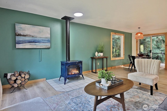 living area with a wood stove, light wood-style floors, and baseboards