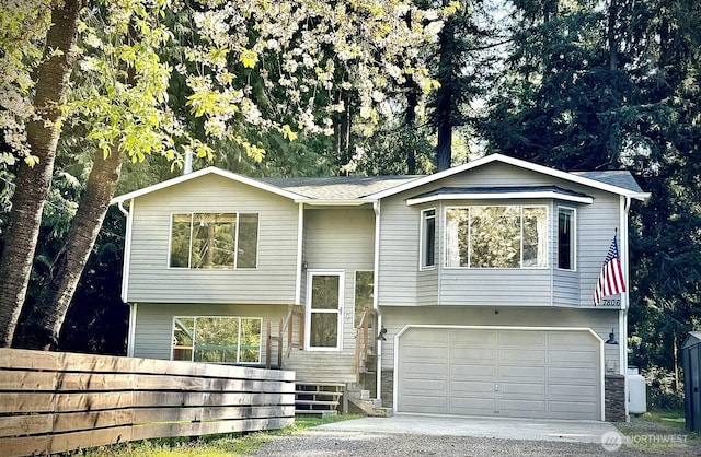 raised ranch with fence, a garage, and driveway