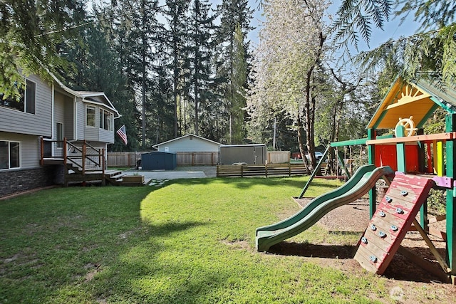 view of yard featuring an outdoor structure, a storage shed, a playground, and fence