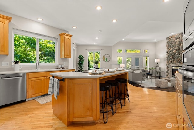 17605 244th Ave SE, Maple Valley, WA 98038 - kitchen with stainless steel dishwasher, light wood finished floors, open floor plan, light countertops, and a breakfast bar area