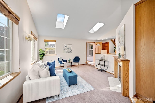 carpeted living area with vaulted ceiling with skylight and baseboards