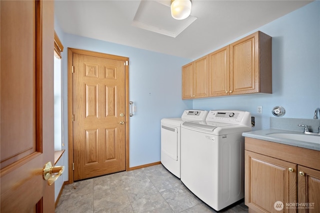 washroom featuring washing machine and dryer, a sink, cabinet space, and baseboards