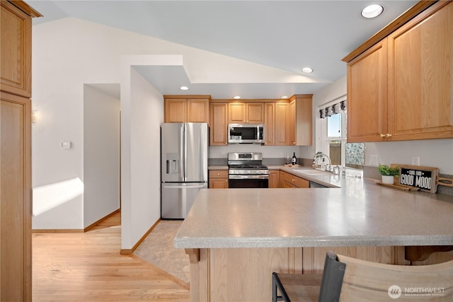 kitchen with lofted ceiling, light wood-style flooring, a sink, a breakfast bar, and stainless steel appliances