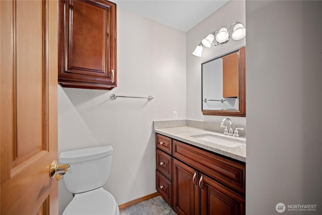 bathroom featuring toilet, vanity, and baseboards