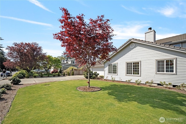 exterior space featuring a garage, a chimney, a front lawn, and concrete driveway