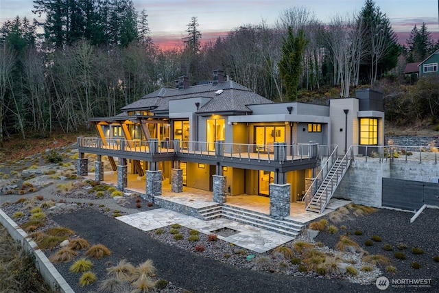 back of house featuring a wooden deck, stairs, a patio, and a chimney
