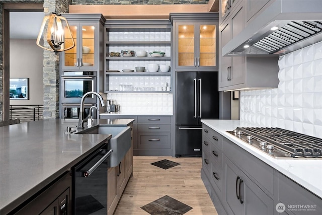 kitchen with gray cabinets, light wood-style floors, appliances with stainless steel finishes, and exhaust hood