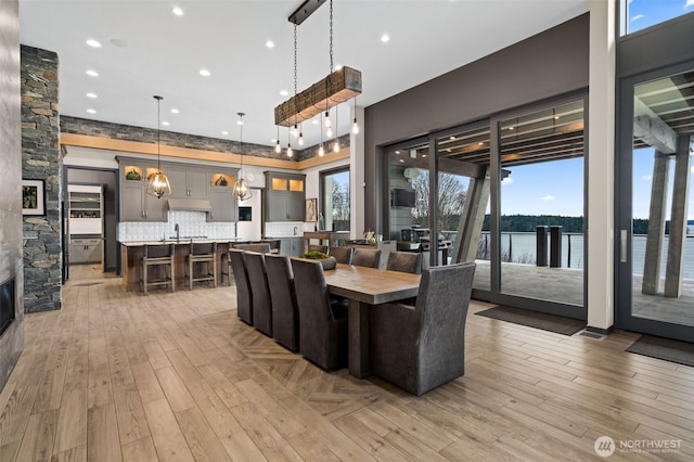 dining room with a water view, recessed lighting, light wood-style floors, and a healthy amount of sunlight