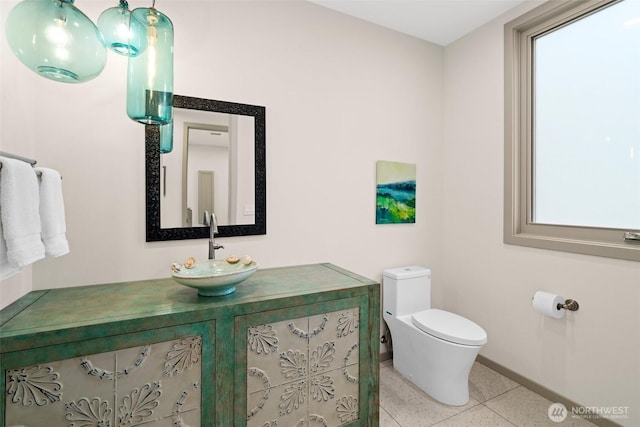 half bathroom featuring vanity, baseboards, and toilet