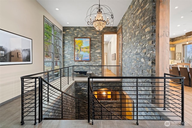 corridor featuring an inviting chandelier, baseboards, an upstairs landing, and recessed lighting