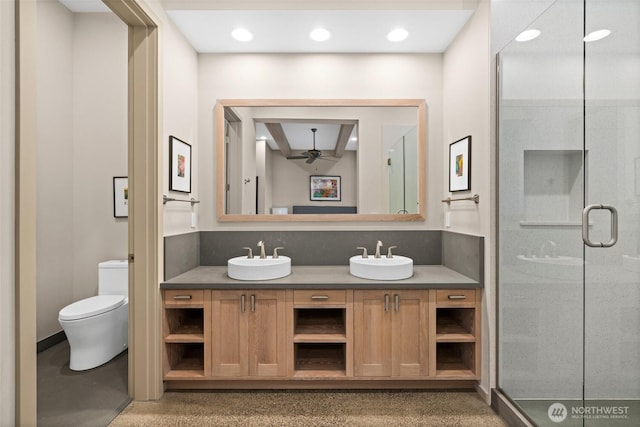 bathroom with a shower stall, a ceiling fan, toilet, a sink, and double vanity