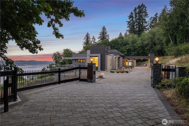 patio terrace at dusk with a water view, a gate, and a fenced front yard