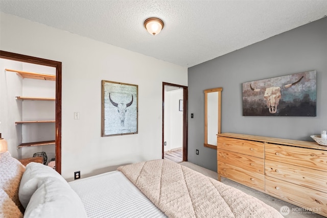 carpeted bedroom featuring a walk in closet and a textured ceiling