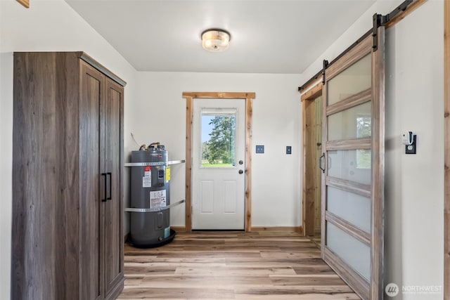 entryway with secured water heater, a barn door, and light wood-style flooring