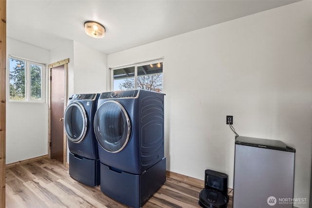 laundry room featuring separate washer and dryer, plenty of natural light, and wood finished floors