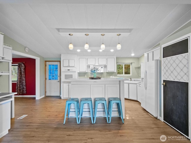 5255 Apollo Rd, Langley, WA 98260 - kitchen with light wood finished floors, white appliances, a breakfast bar, light countertops, and white cabinets