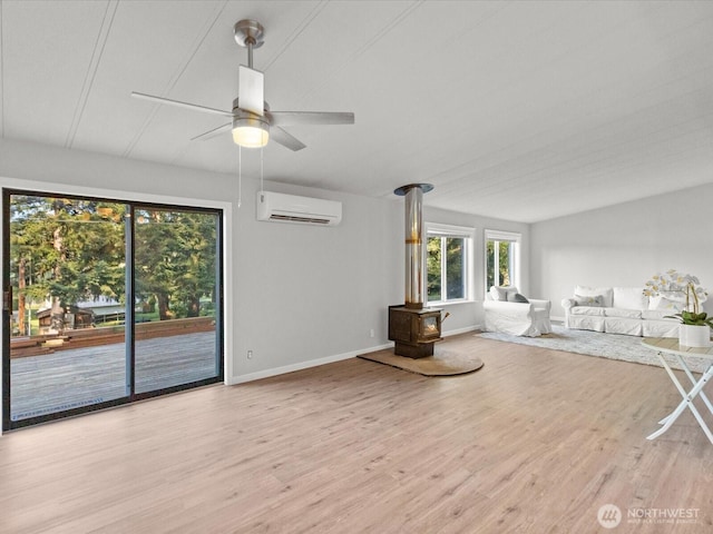 5255 Apollo Rd, Langley, WA 98260 - unfurnished living room with a wall unit AC, a wood stove, baseboards, wood finished floors, and a ceiling fan