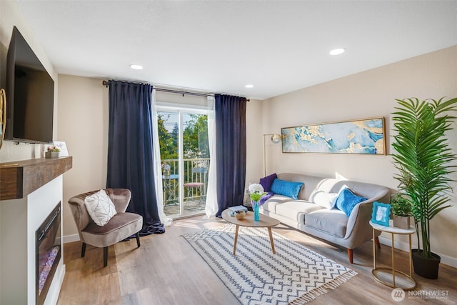 living area featuring recessed lighting, a fireplace, baseboards, and wood finished floors