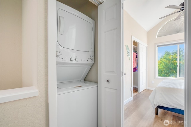 laundry room with baseboards, ceiling fan, stacked washer / dryer, laundry area, and light wood finished floors