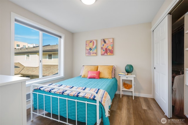 bedroom with a closet, baseboards, and wood finished floors