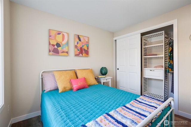 bedroom with wood finished floors, baseboards, and a closet