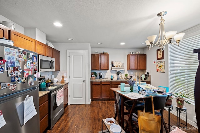 1713 17th St, Everett, WA 98201 - kitchen featuring brown cabinets, appliances with stainless steel finishes, a chandelier, and dark wood-type flooring