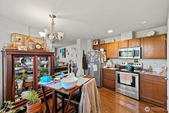 1713 17th St, Everett, WA 98201 - kitchen with a chandelier, brown cabinetry, decorative backsplash, stainless steel appliances, and wood finished floors