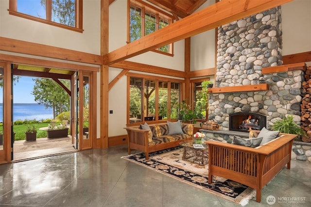 living room with a water view, a high ceiling, and a stone fireplace
