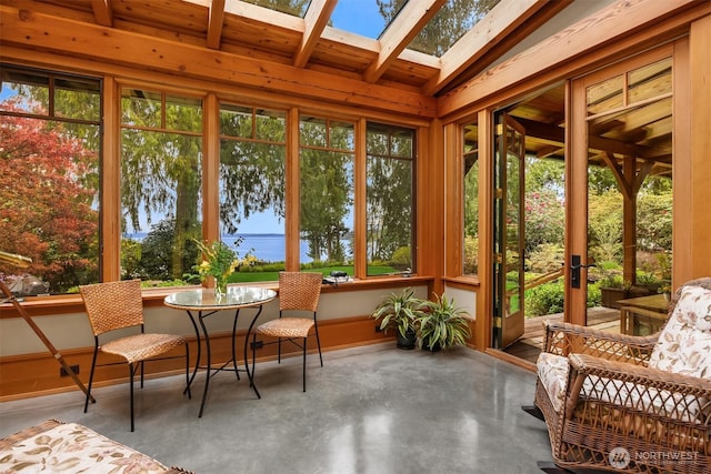 sunroom / solarium with healthy amount of natural light, finished concrete flooring, a skylight, and beamed ceiling