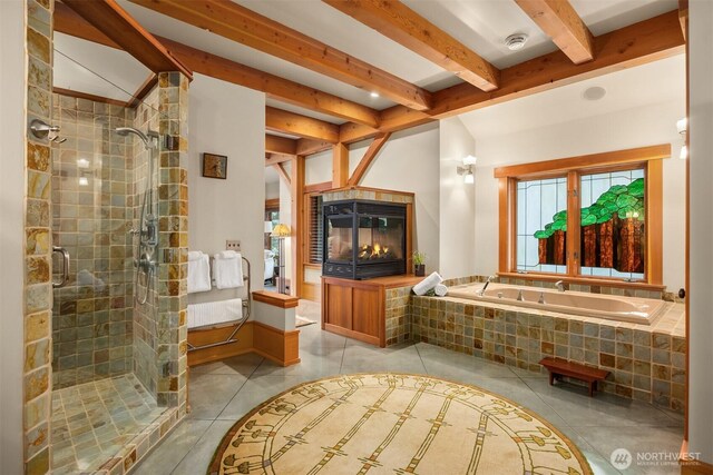bathroom featuring tile patterned flooring, a bath, a shower stall, beam ceiling, and a tile fireplace