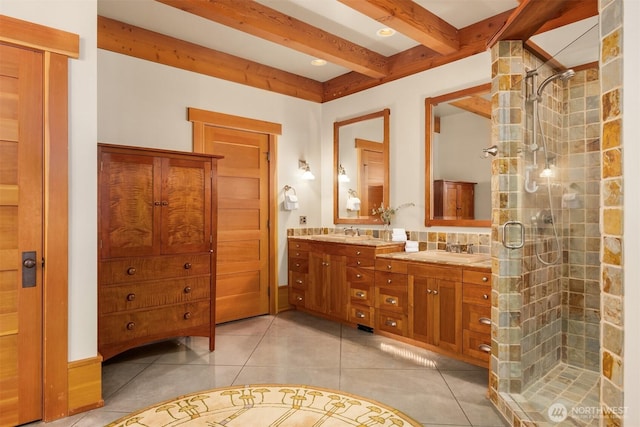 bathroom with double vanity, a shower stall, beam ceiling, and tile patterned floors