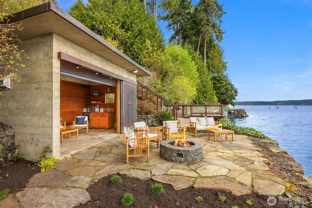 view of patio / terrace with a fire pit, stairway, and a water view