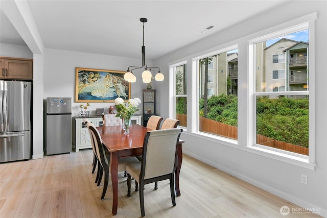 dining space with baseboards, an inviting chandelier, a healthy amount of sunlight, and light wood-style flooring