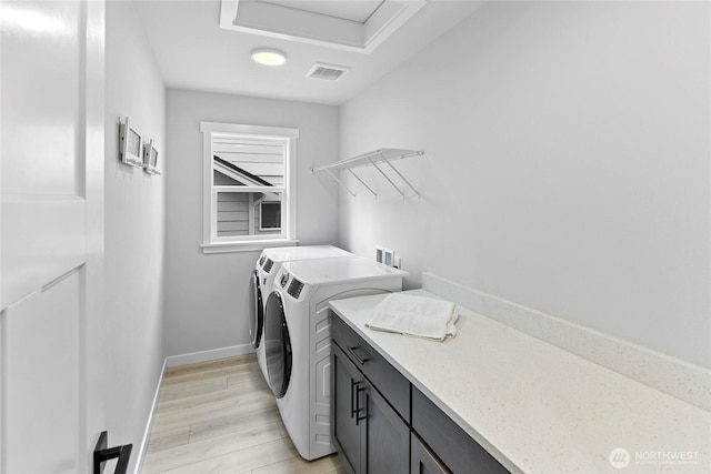 clothes washing area featuring cabinet space, separate washer and dryer, baseboards, light wood-type flooring, and visible vents