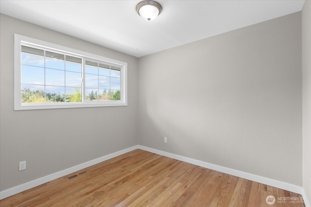 empty room featuring light wood-style flooring, baseboards, and visible vents