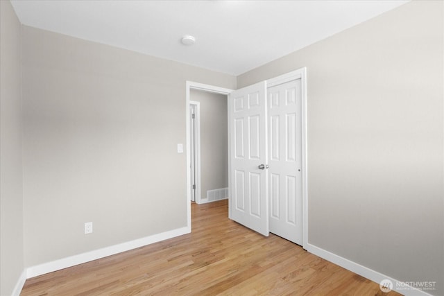unfurnished bedroom featuring light wood-style flooring, visible vents, baseboards, and a closet