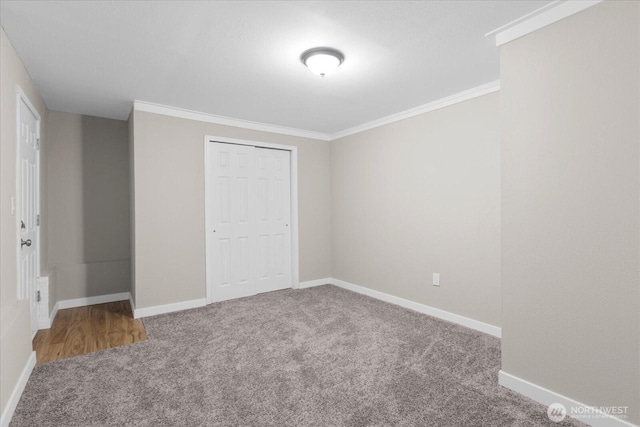 unfurnished bedroom with crown molding, a closet, baseboards, and carpet