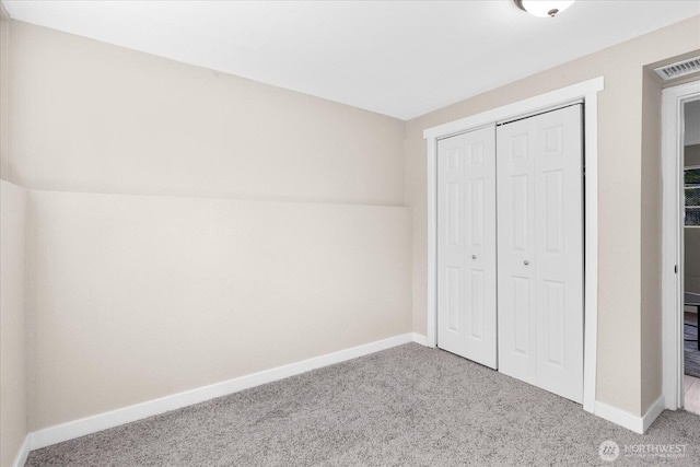 unfurnished bedroom with a closet, baseboards, visible vents, and carpet floors