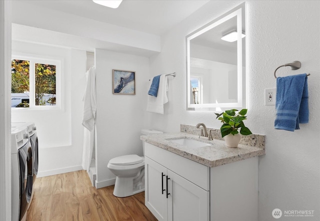 full bath with vanity, toilet, wood finished floors, washer and dryer, and baseboards