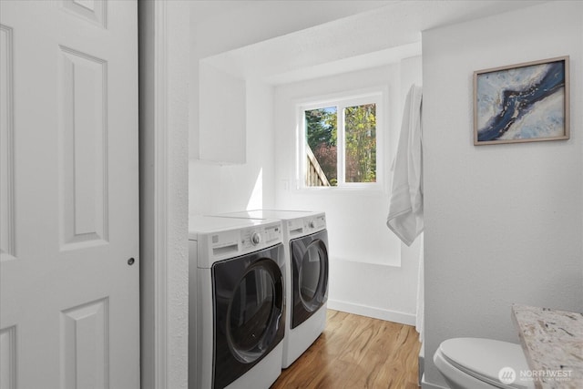 washroom with laundry area, light wood finished floors, baseboards, and washer and clothes dryer