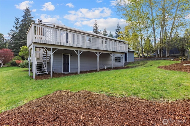 rear view of property featuring a yard, stairway, and a deck