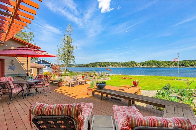 deck with outdoor dining area and a water view
